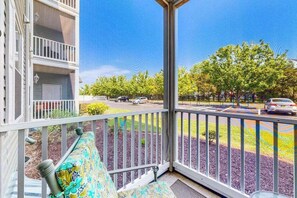 Un balcon donnant sur un parking et des arbres.