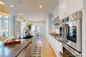 A modern kitchen with stainless steel appliances, pendant lighting, and a central island. - Arbor-Lyn house w/shared pool, deck, patio, ping-pong table, grill (Rehoboth Beach)