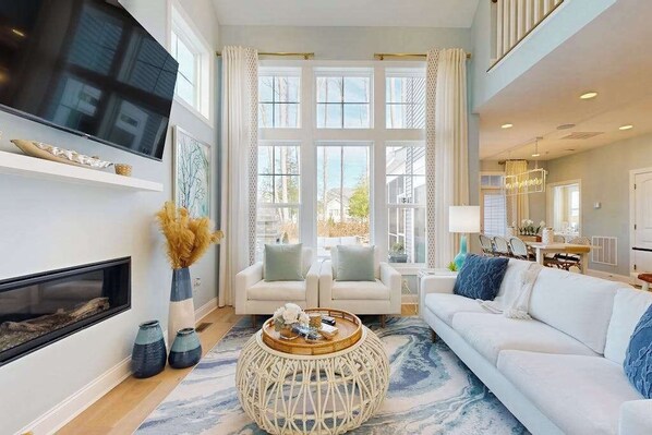A modern living room with a fireplace, a large TV, and a sofa. - Arbor-Lyn house w/shared pool, deck, patio, ping-pong table, grill (Rehoboth Beach)