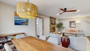 Un salon moderne comprenant un coin repas, une cheminée et un ventilateur de plafond.