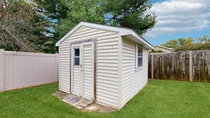 Un petit abri de plain-pied, doté d’une porte et de fenêtres, entouré d’une clôture en bois et d’une cour gazonnée.