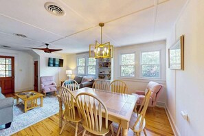 A dining area with a table and chairs, a ceiling fan, and a bookshelf. - Town of Rehoboth Beach house w/screen porch, walk to beach & restaurants (Rehoboth Beach)