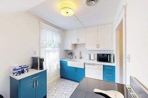 A modern kitchen with blue cabinets, a microwave, a coffee maker, and a dishwasher. - Town of Rehoboth Beach house w/screen porch, walk to beach & restaurants (Rehoboth Beach)