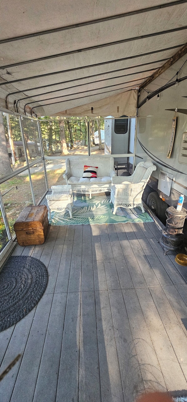 A covered deck with wicker furniture, a table, and a suitcase.