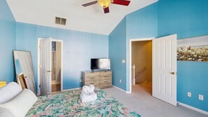 A bedroom with a bed, a dresser, a television, and a ceiling fan. - Rehoboth Crossing townhouse with pool, gym, balcony, grill, W/D, bikes, & patio (Rehoboth Beach)