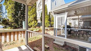 Un patio techado con vistas a una casa, mobiliario exterior y una parrilla.