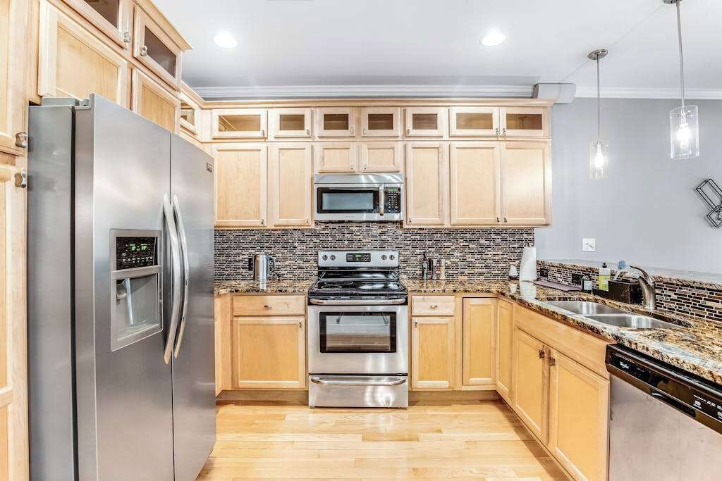 Una cocina con armarios de madera, electrodomésticos de acero inoxidable, microondas y lavavajillas.