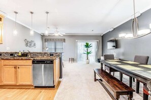 Une cuisine moderne équipée d’un lave-vaisselle, d’une table à manger avec des chaises et d’un ventilateur de plafond.