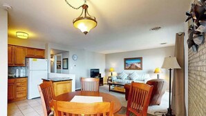Un espacio habitable compacto con comedor, cocina y sala de estar con sofá y un cuadro.