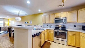 A modern kitchen with wooden cabinets, stainless steel appliances, and a central island. - The Palms water-view condo near beach with outdoor pool, streaming, W/D, & AC (Rehoboth Beach)