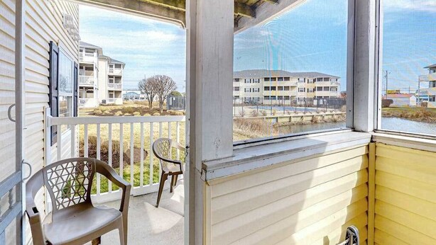 A balcony with a view of buildings and a tree. - The Palms water-view condo near beach with outdoor pool, streaming, W/D, & AC (Rehoboth Beach)