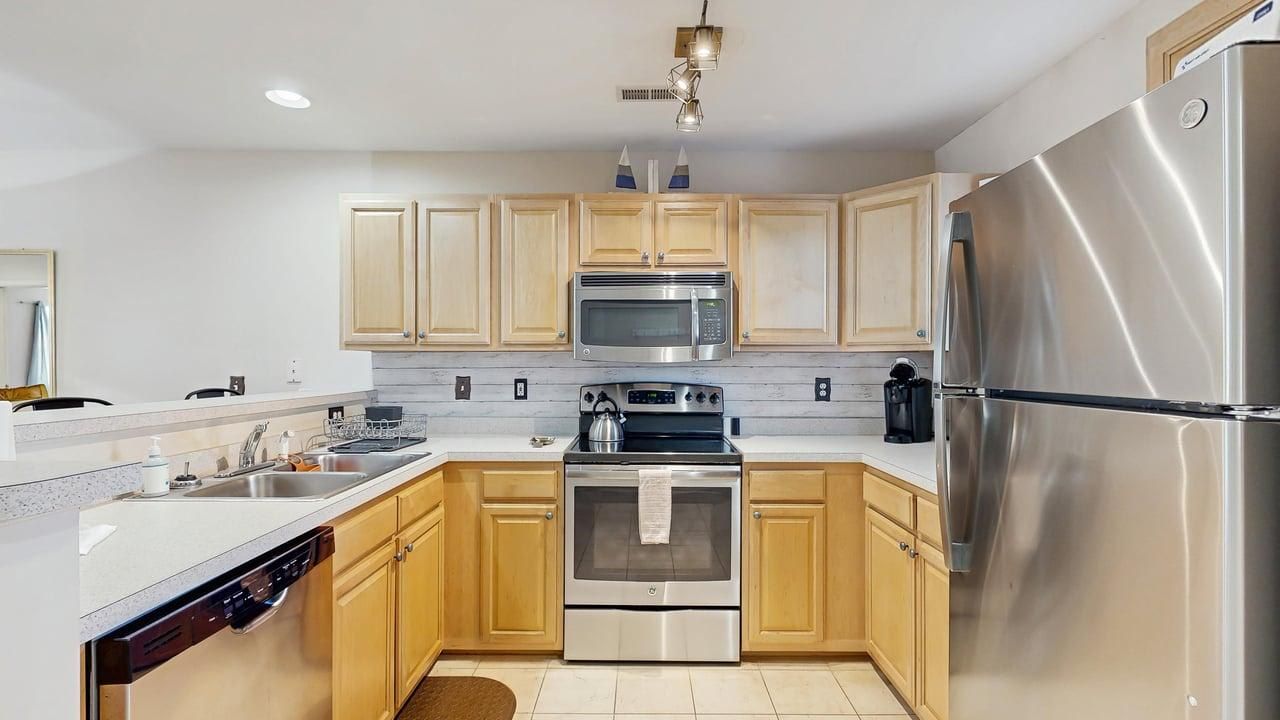 A modern kitchen with wooden cabinets, stainless steel appliances, a dishwasher, and a refrigerator.