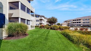 A residential building with multiple balconies, a well-maintained lawn, and a fenced swimming pool area.