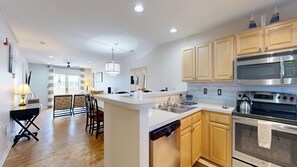 A modern kitchen with wooden cabinets, stainless steel appliances, and a central island. - The Palms water-view condo near beach with outdoor pool, streaming, W/D, & AC (Rehoboth Beach)