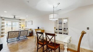A dining area with a white table and chairs, a chandelier, and a large mirror. - The Palms water-view condo near beach with outdoor pool, streaming, W/D, & AC (Rehoboth Beach)