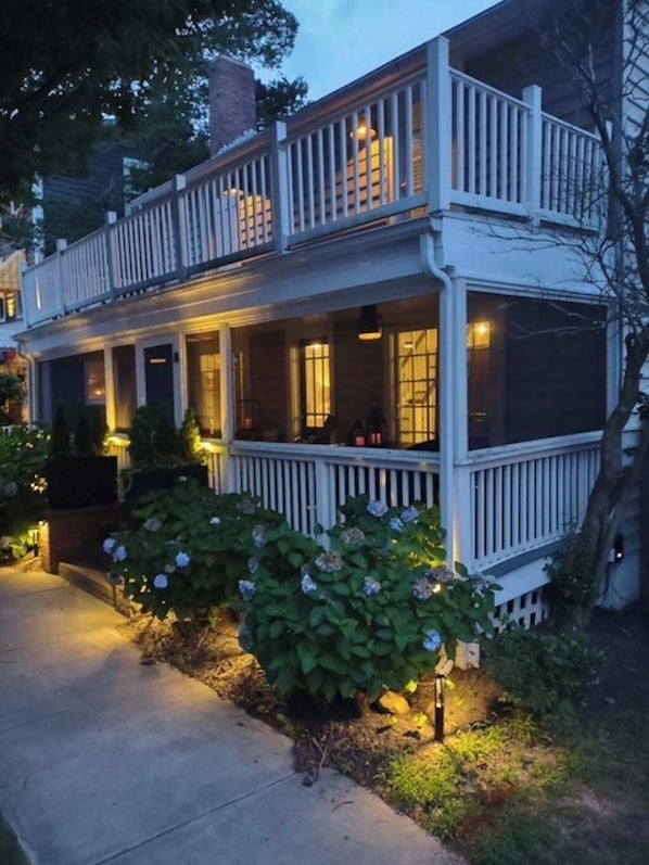 A two-story house with a balcony, a porch, and a well-lit entrance. - Rehoboth Beach home near beach with decks, yard & W/D - dog-friendly (Rehoboth Beach)
