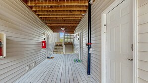 A covered wooden corridor with a white door, a red fire extinguisher, and a green mat at the end. - Eagles Landing comfy condo with pools and tennis courts - 1 mile to beach (Rehoboth Beach)