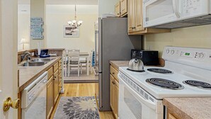 A kitchen with a refrigerator, microwave, stove, and sink. - Eagles Landing comfy condo with pools and tennis courts - 1 mile to beach (Rehoboth Beach)
