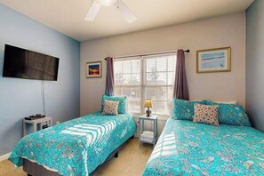 A bedroom with two beds, a TV, a window with curtains, and a small table with a lamp. - Spacious Creekwood condo with shared pool, Balcony, W/D & Free WIFI (Rehoboth Beach)