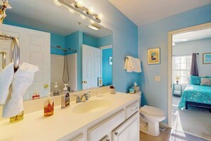 A bathroom with a sink, mirror, and toilet. There is a shower visible in the background. - Spacious Creekwood condo with shared pool, Balcony, W/D & Free WIFI (Rehoboth Beach)