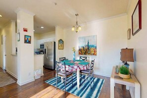 A dining area with a table set for four, a chandelier, and a painting on the wall. - Spacious Creekwood condo with shared pool, Balcony, W/D & Free WIFI (Rehoboth Beach)