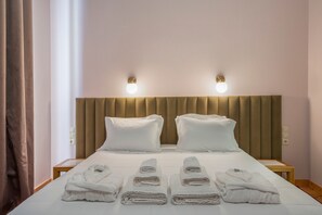 Et hotelværelse med en seng, to sengeborde, en sengegavl og fire håndklæder på sengen.
