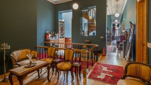 A room with a wooden staircase, a dining table with chairs, a red rug, and a large mirror. - Queen Messene – Room with King-Size Bed and Balcony (Kalamata)