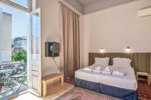 Et hotelværelse med seng, sengebord, bænk, fjernsyn og udsigt ud