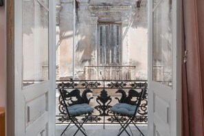 An open balcony with wrought iron railings and two cushioned chairs.