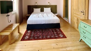 A bedroom with a bed, bedside tables, a TV, a wooden wardrobe, and a red patterned rug. - Prince Antilochus – King-Size Bed Room with Balcony (Kalamata)