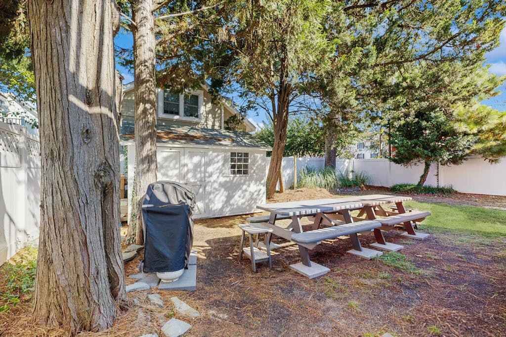 A backyard with a picnic table and a barbecue grill.