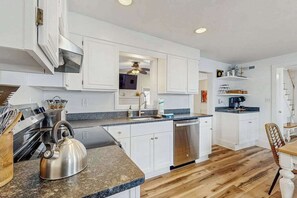 A modern kitchen with white cabinets, granite countertops, a stainless steel kettle, and a dishwasher. - Town of Rehoboth Beach spacious house w/patio, W/D & WIFI (Rehoboth Beach)