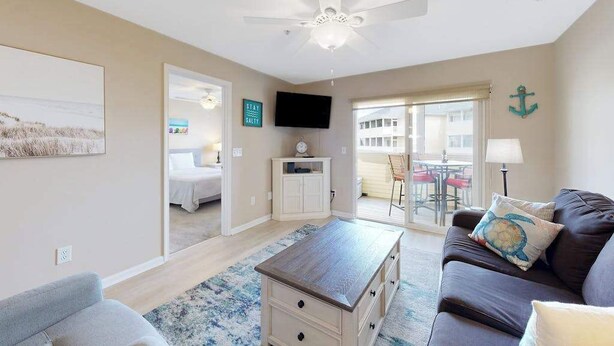 Un salon doté d’un ventilateur de plafond, d’une télévision, d’un canapé, d’une table basse et donnant sur un balcon.
