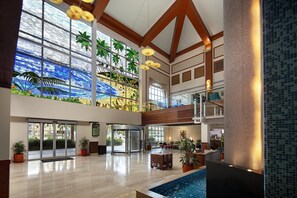 Eine geräumige Lobby mit einer großen Glaswand, einem Pool und einer Treppe.