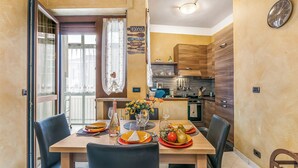 Een eetgedeelte met een tafel voor vier personen, een keuken op de achtergrond en een wandklok.
