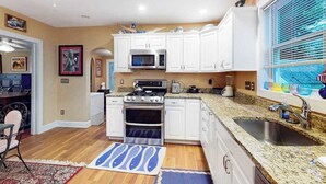 A kitchen with white cabinets, a microwave, stove, and granite countertops. - Dog-friendly 2-story home near beach with screened porch, fast WiFi, W/D, & AC (Rehoboth Beach)
