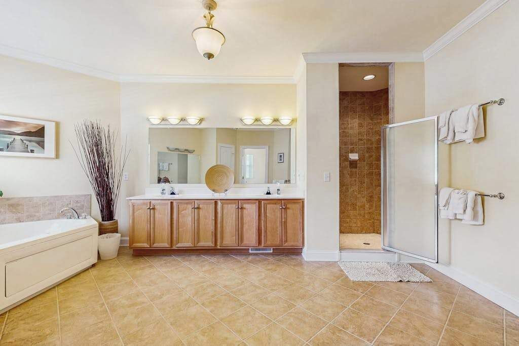 Een badkamer met een bad, douche, wastafel met spiegel en een handdoekrek.
