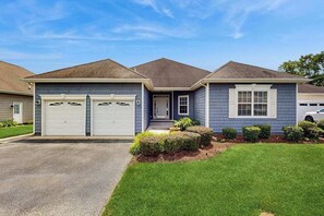 Une maison à deux étages avec un garage, un porche à l’avant et une pelouse bien entretenue.
