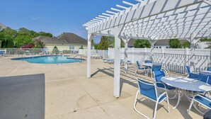 An outdoor pool area with a pergola, lounge chairs, and tables. - Keys of Marsh Harbor house w/community pool & tennis court, deck, grill (Rehoboth Beach)