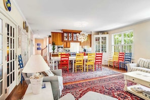 A spacious living area with a dining table, colorful chairs, a sofa, and a large rug. - Rehoboth Beach North Shores home with pool, basketball, fast WiFi & W/D (Rehoboth Beach)