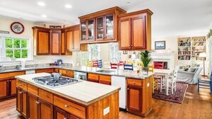 Una cocina amplia con armarios de madera, una isla central y un comedor con sillas.