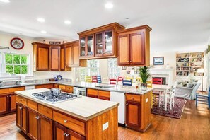 A spacious kitchen with wooden cabinets, a central island, and a dining area with chairs. - Rehoboth Beach North Shores home with pool, basketball, fast WiFi & W/D (Rehoboth Beach)