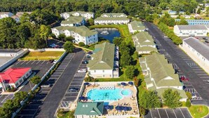 An aerial view of a residential area with a swimming pool, multiple buildings, and a parking lot. - The Tides spacious condo w/shared pool, close to restaurants & shopping (Rehoboth Beach)