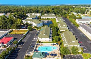 An aerial view of a residential area with a swimming pool, multiple buildings, and a parking lot. - The Tides spacious condo w/shared pool, close to restaurants & shopping (Rehoboth Beach)