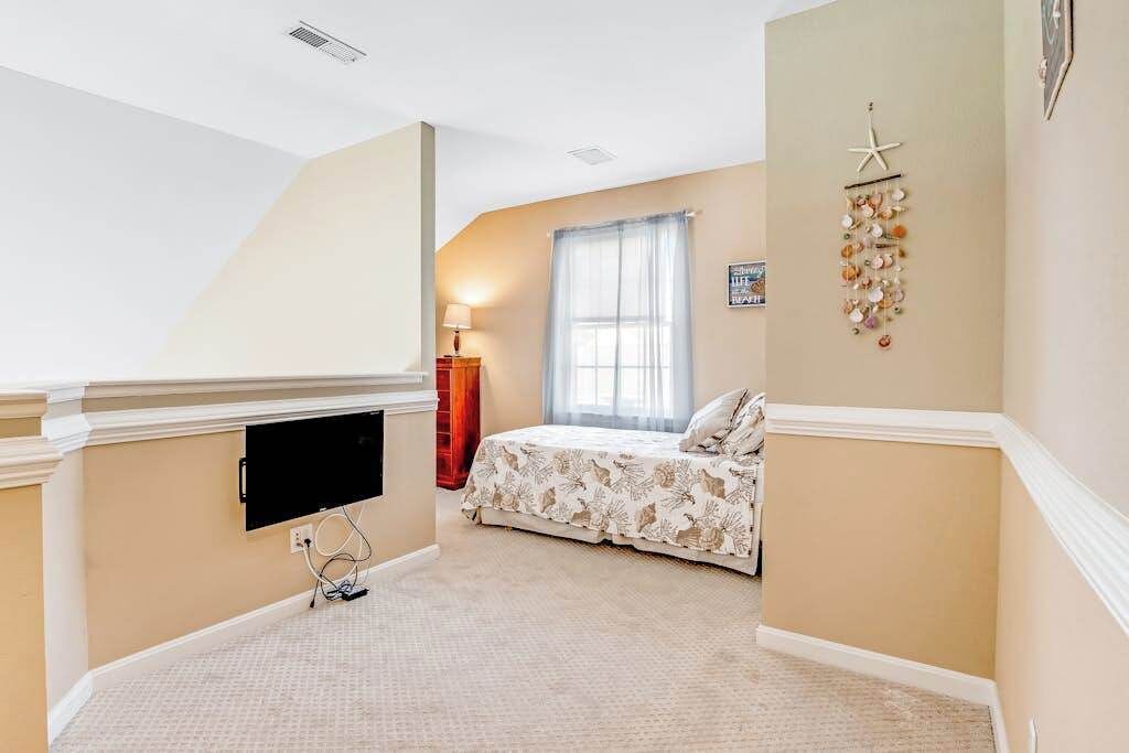 A bedroom with a bed, a TV mounted on the wall, a starfish decoration, and a window with curtains.