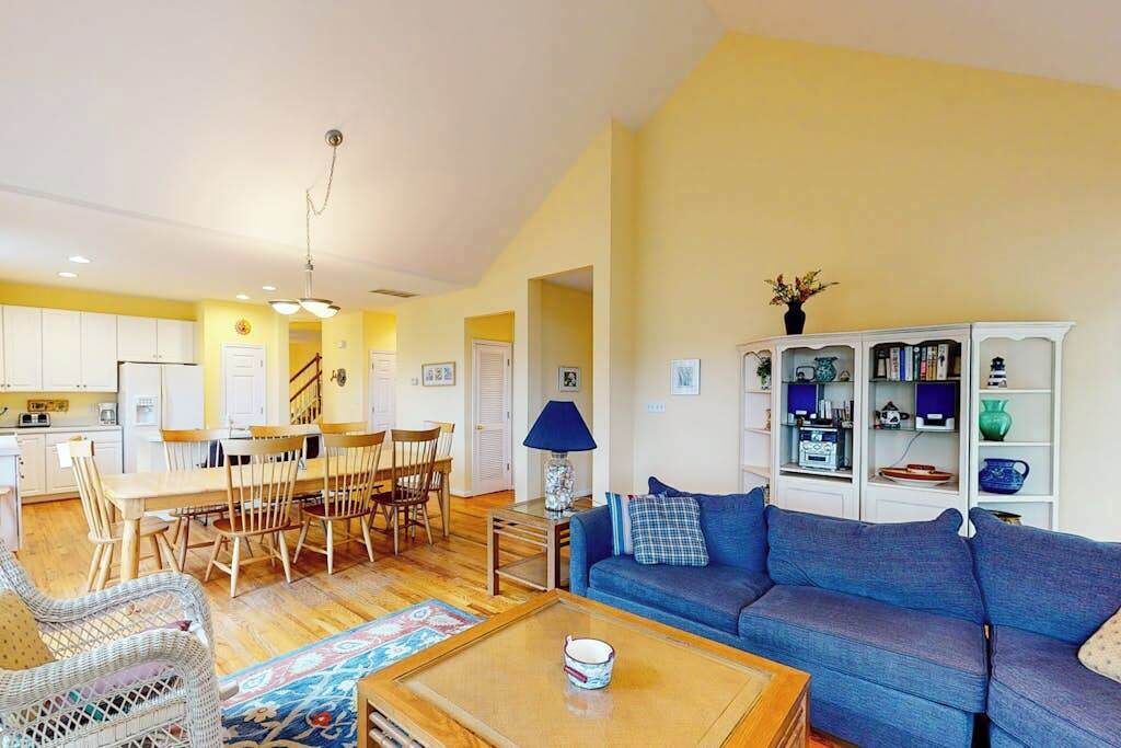 A living room with a sofa, coffee table, and dining area with chairs and a table.