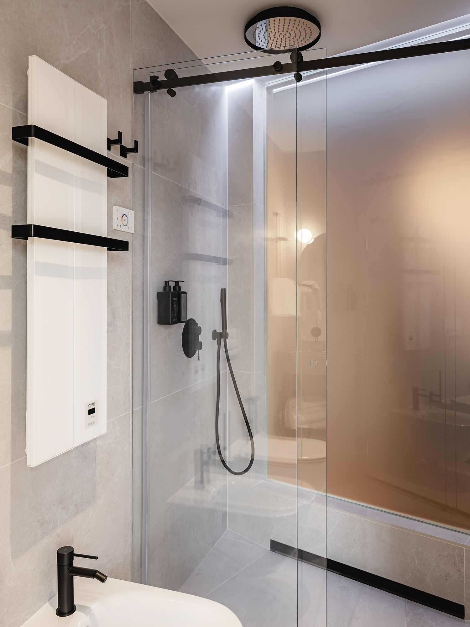 A modern bathroom with a glass-enclosed shower, a white sink, and a black faucet.
