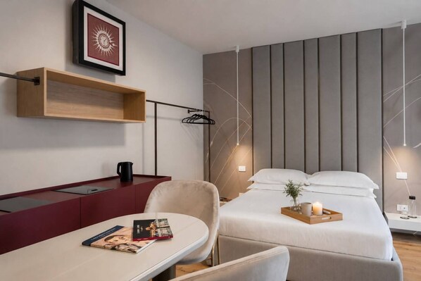 Una habitación de hotel moderna con una cama, una mesita de noche, una silla y un escritorio con una computadora.