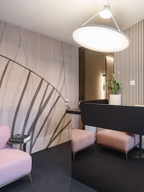 Una habitación de hotel moderna con una pared curva, un sofá negro, una mesita pequeña y una lámpara colgante grande.