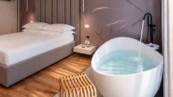 Quarto moderno com uma cama grande, um banco de madeira, uma banheira e um aplique.